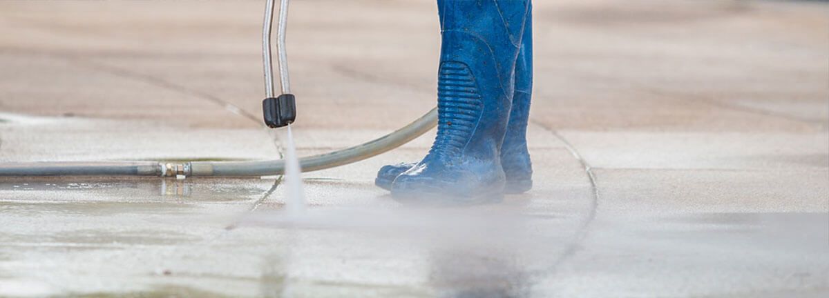 A worker power washing the floor