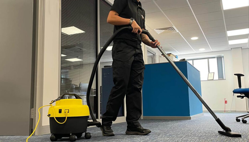 A cleaner vacuum cleaning an office
